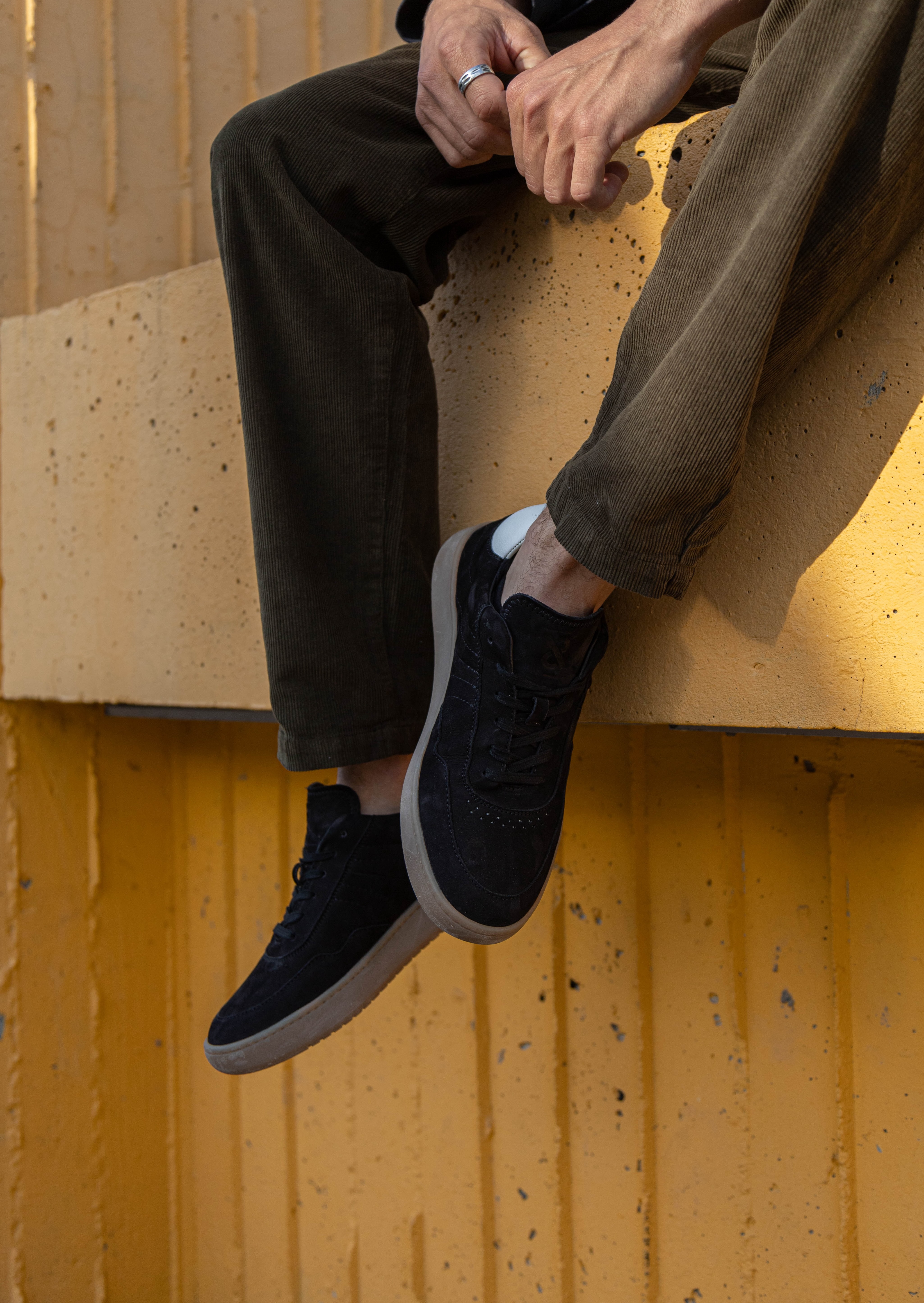 A man's legs hanging off a ledge featuring the simple & strange sneaker.