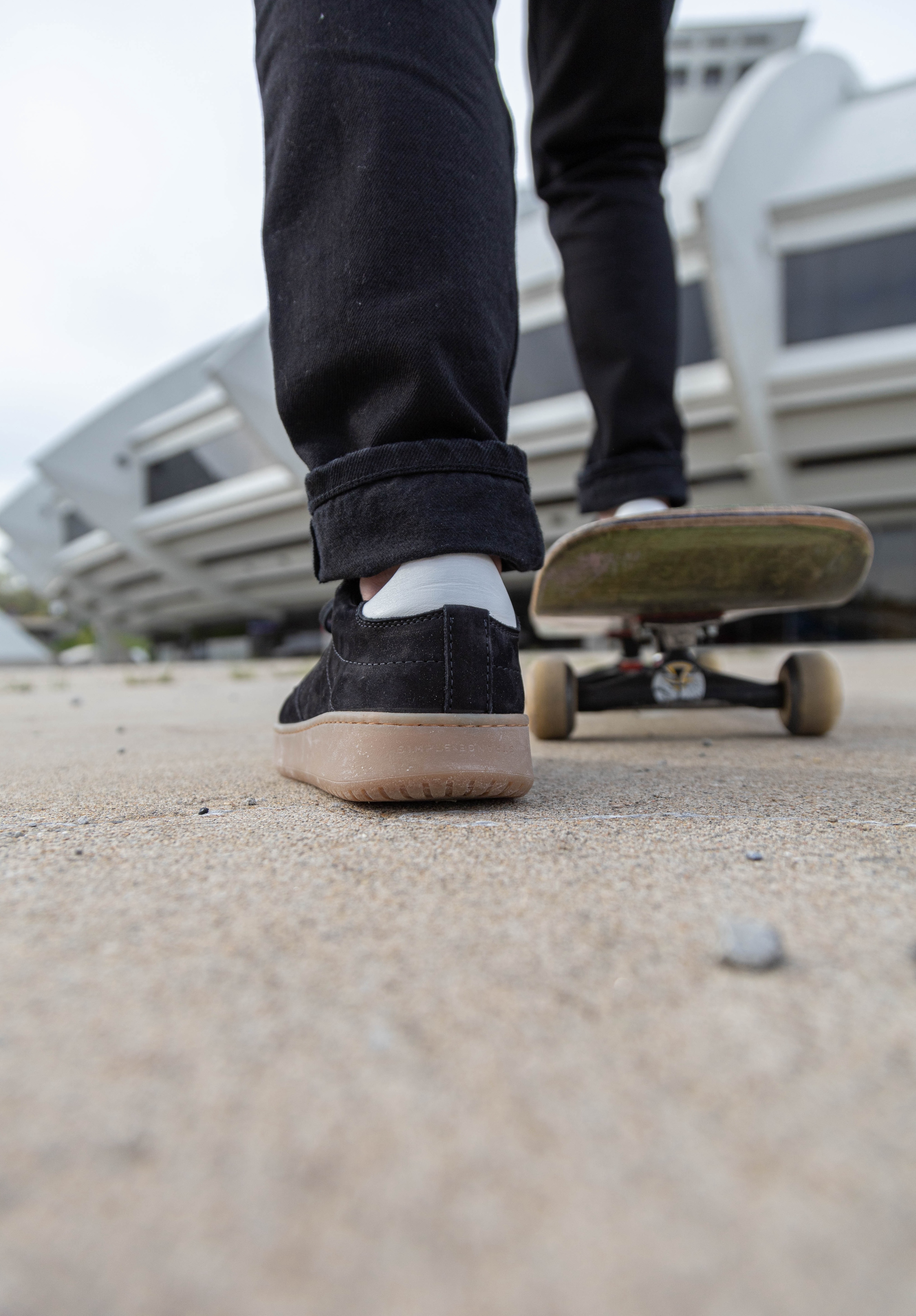 A person wearing pair of simple & strange sneaker getting ready to push off on a skateboard.