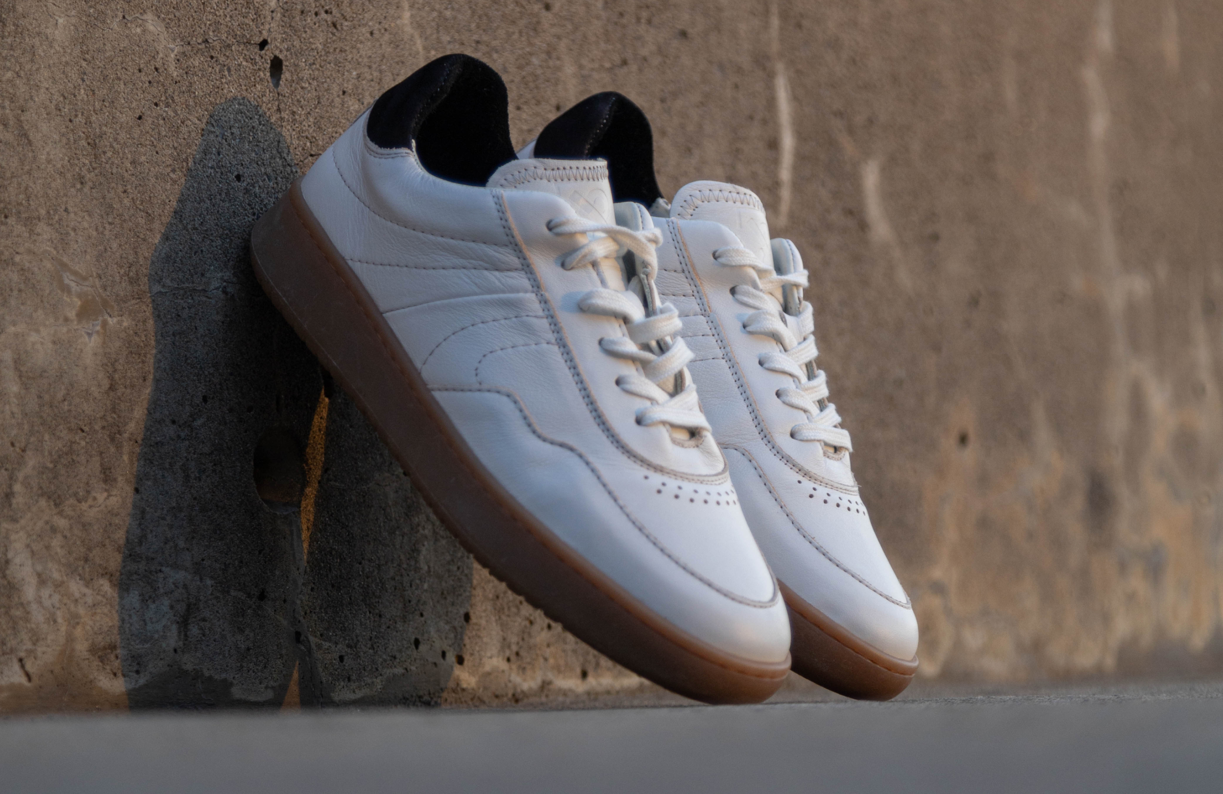 A pair of simple & strange sneakers leaning on a wall.